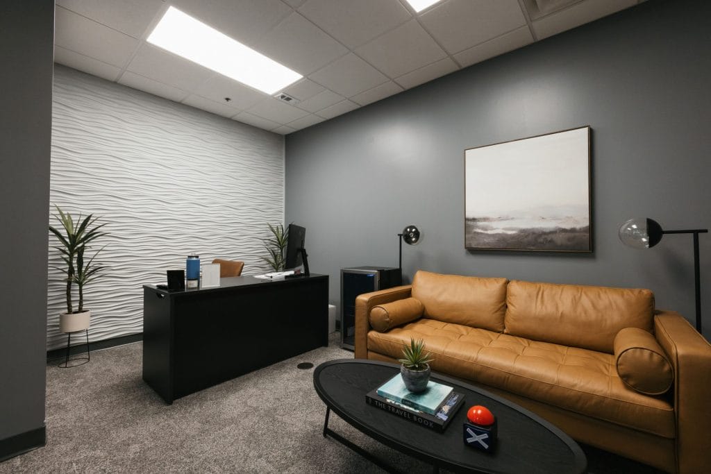 Office reception area with textured white feature wall, leather sofa and reception desk